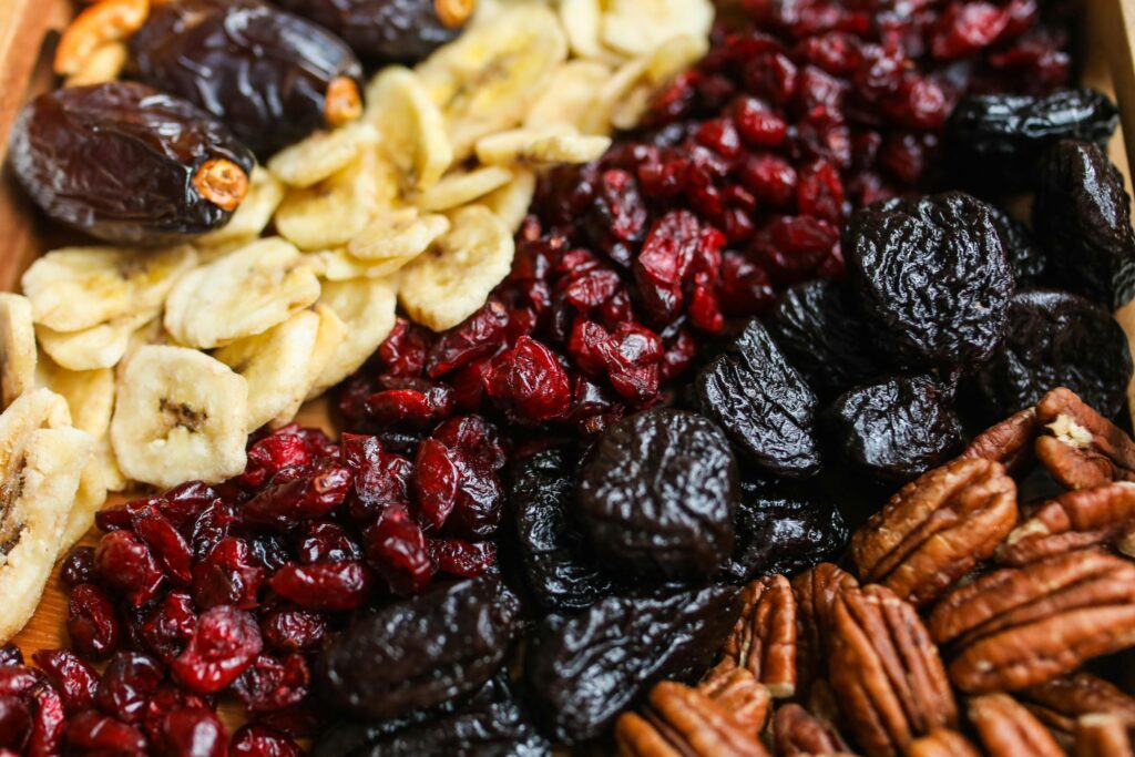 Vibrant mix of dried fruits and nuts on a wooden tray, perfect for healthy snacking.